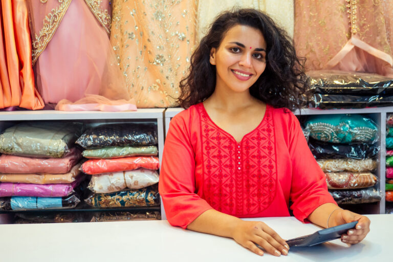 indian seller women in red kurta stand in her studio showroom .
